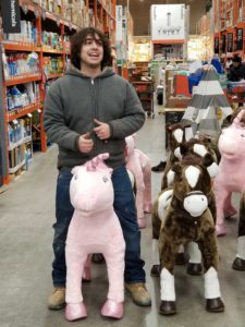 Patrick's helper "Vinegar" Victor being silly, sitting on a toy unicorn at Home Depot