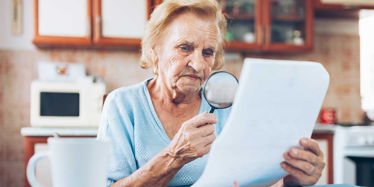 An elderly woman examines her Toronto water bill with a magnifying glass